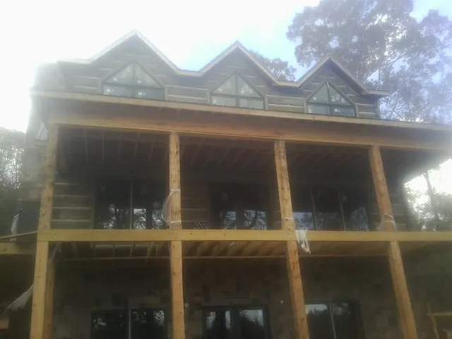 Dormers and porch framing on a large log home under construction — Roof Coating work by our crew in Saratoga