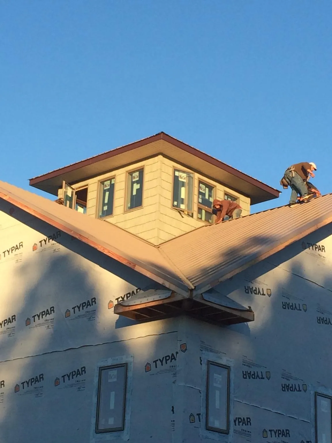 Roofers working around a rooftop cupola on a new metal roof at sunset — Roof Waterproofing in Saratoga by Roofing Brothers